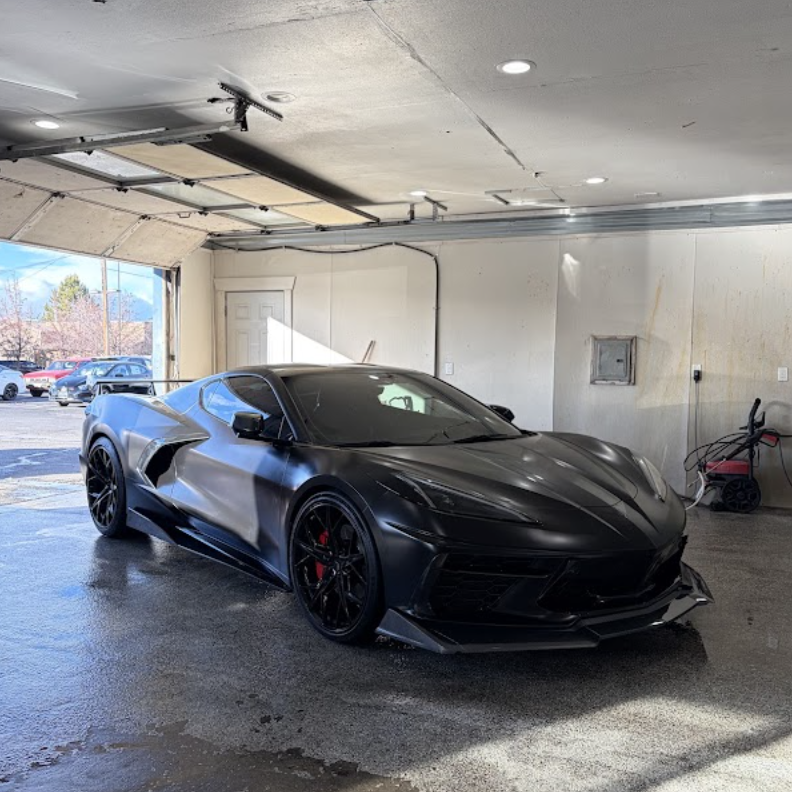 Black sports car after a full mobile detail in a home garage